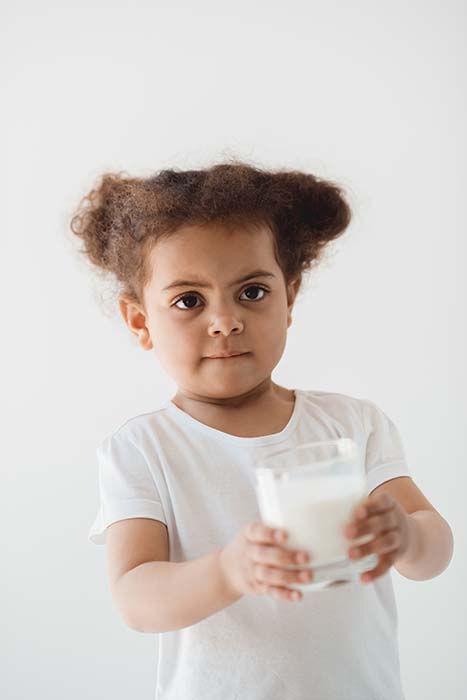 The Best Milk for Babies After 1 | New Ways Nutrition Toddler holding out a glass of milk