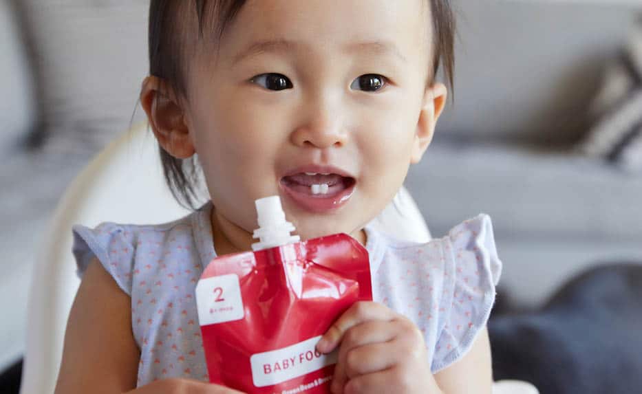 Toddler with baby food pouch in her hands