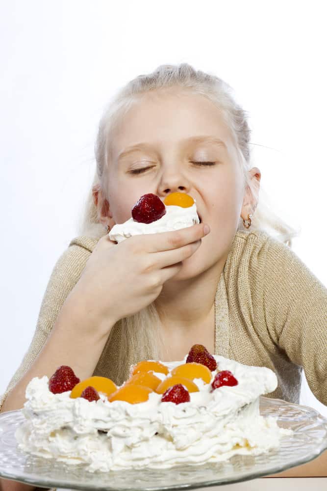 young girl eating a piece of cake with eyes closed