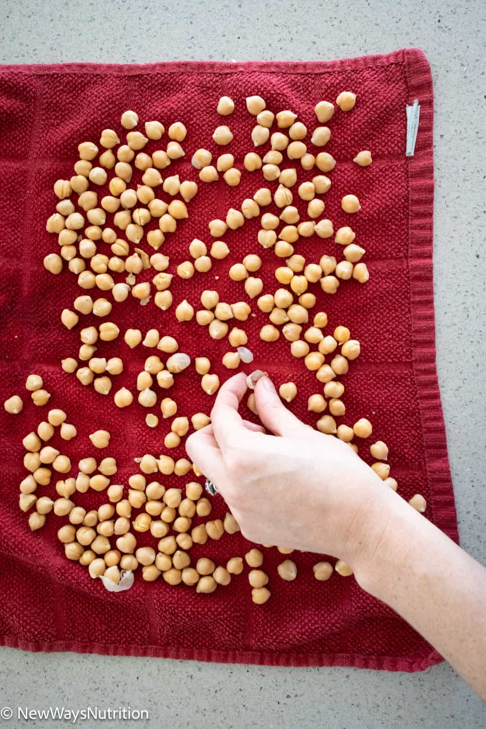 chickpeas on red towel with hand picking out a skin