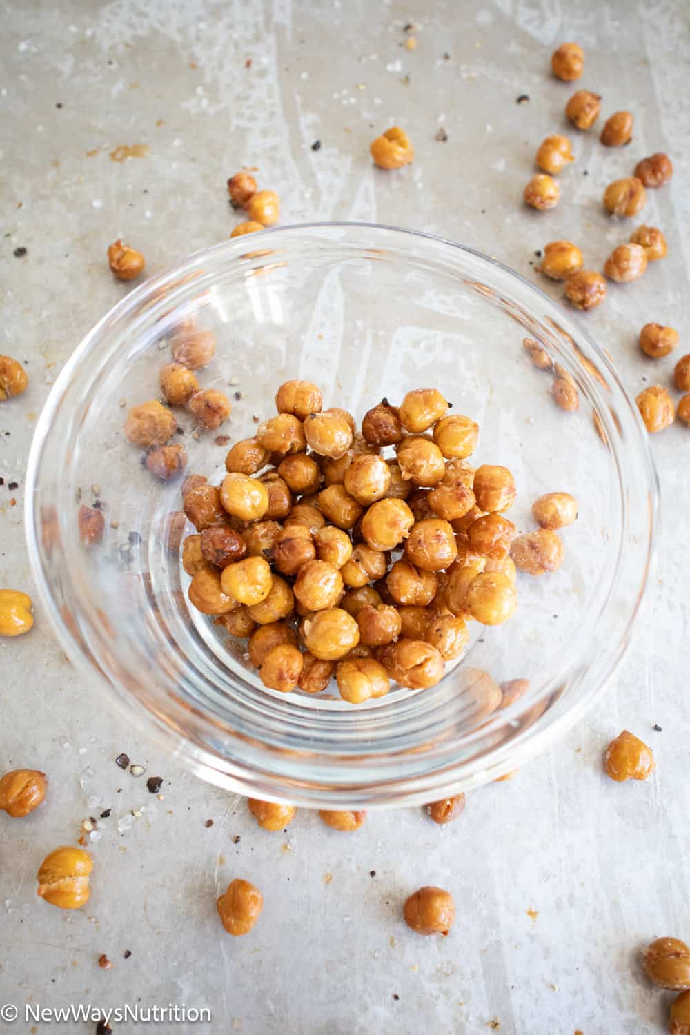 close up of roasted chickpeas in glass bowl on sheet pan